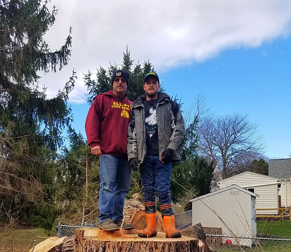 Owner Scott Drake and son Scottie standing on a large tree stump